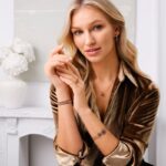 Na zdjęciu przedstawiona jest kobieta w stylowej biżuterii, w tym naszyjniku, bransoletch i kolczykach, pozująca w eleganckim miejscu. Zdjęcie zapewnia luksusową atmosferę i wyrafinowanie, które mogą być symbolami pozycji marki. Apart przejmuje Jubitom, a zdjęcie może nawiązywać do wartości transakcji.