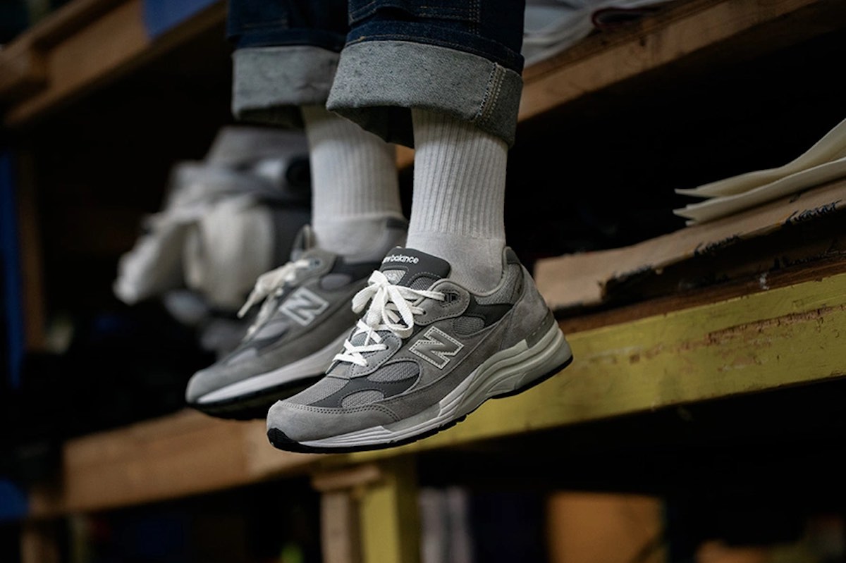Sneakersy New Balance 992. Szary model na stopach mężczyzny w granatowych jeansach i białych skarpetach.