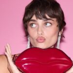 Victoria's Secret otworzy pierwszy sklep w Poznaniu w CH Posnania. Na zdjęciu modelka VS z krótkimi włosami, pozująca z torebką w kształcie ust.